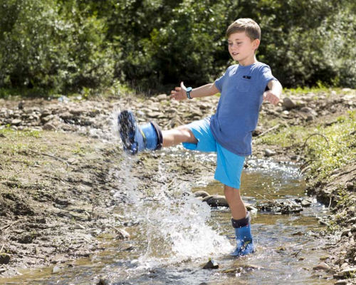 Dětské holínky Demar - dítě v dešti s barevnými gumáky